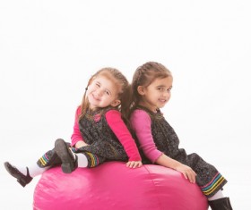 Little sisters sitting in inflatable chair Stock Photo