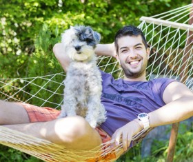 Man and pet dog lying on hammock Stock Photo