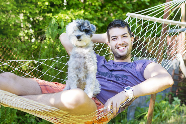 Man and pet dog lying on hammock Stock Photo