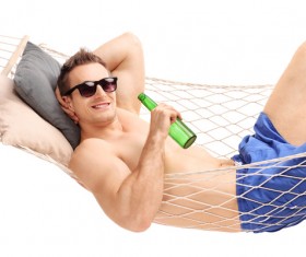 Man lying in a hammock and drinking beer Stock Photo