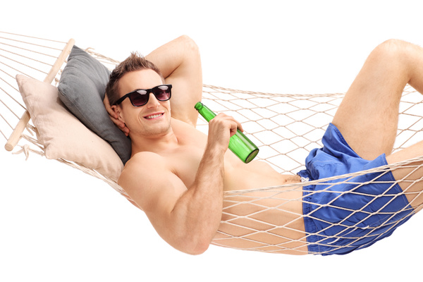 Man lying in a hammock and drinking beer Stock Photo