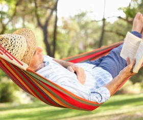 Man lying in hammock reading Stock Photo 01
