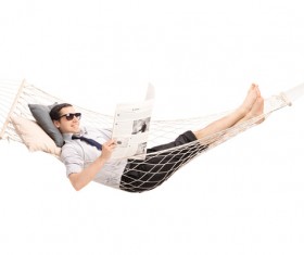 Man lying in hammock reading newspaper Stock Photo
