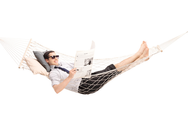 Man lying in hammock reading newspaper Stock Photo