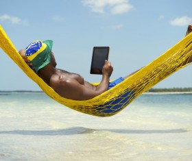 Man lying in hammock using Tablet PC Stock Photo