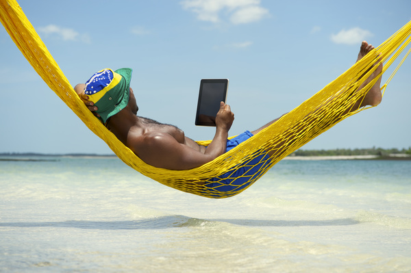 Man lying in hammock using Tablet PC Stock Photo
