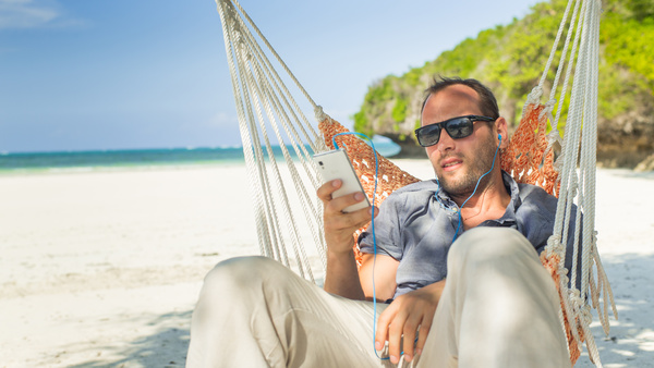Man relaxing in hammock listening to music Stock Photo