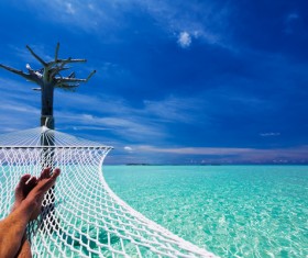 Man resting in hammock over blue sea Stock Photo