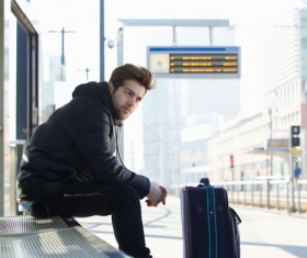 Man sitting at the station waiting for the car Stock Photo