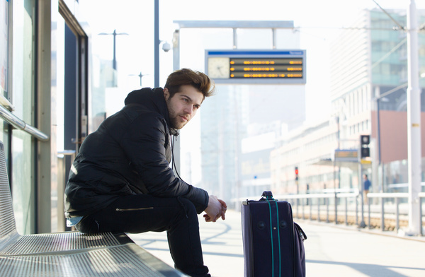 Man sitting at the station waiting for the car Stock Photo