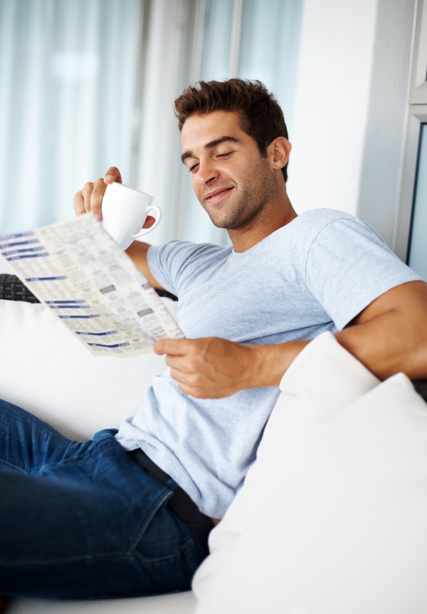 Man sitting on sofa reading morning newspaper Stock Photo