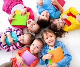 Pupils holding books lying on the floor Stock Photo