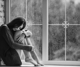 Rainy days sitting on the windowsill girl Stock Photo