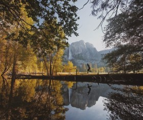 Reflection man jumping on calm lake surface Stock Photo
