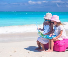 Two little girls sitting on suitcases looking at map Stock Photo