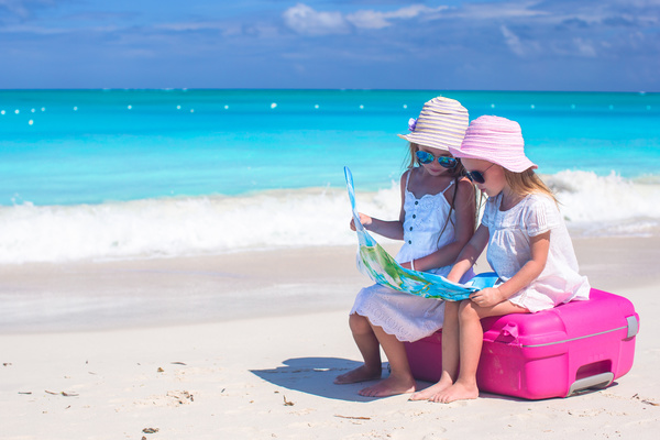 Two little girls sitting on suitcases looking at map Stock Photo