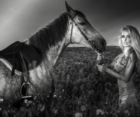 Woman and horse standing in the grass Stock Photo
