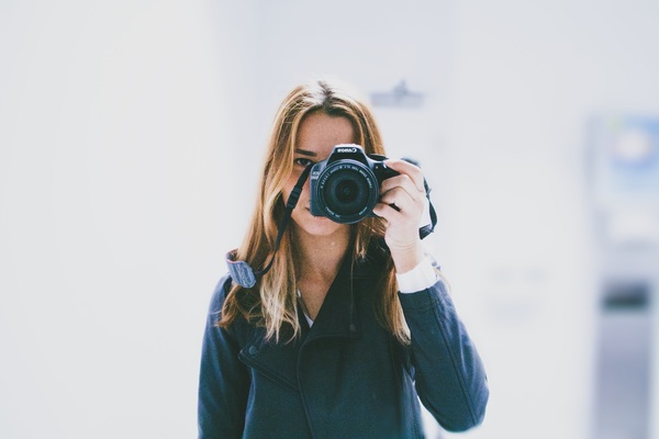Woman holding camera to take picture Stock Photo
