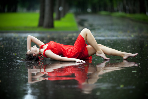 Woman lying on the road on a rainy day Stock Photo