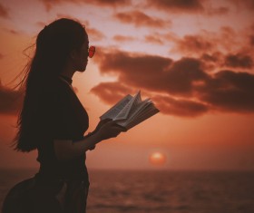 Young girl posing with book on sea sunset Stock Photo
