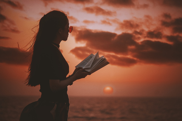 Young girl posing with book on sea sunset Stock Photo