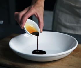 hand pouring sauce into dish Stock Photo