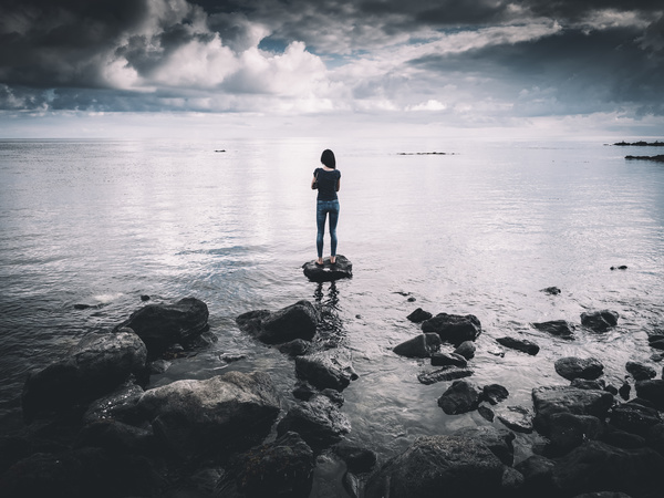woman standing on rocky beach Stock Photo