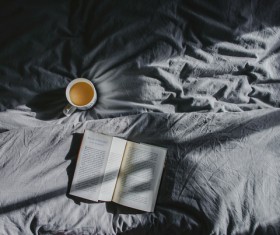 Coffee cup and open book on bed Stock Photo