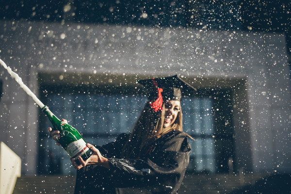 Girl excited with cheering champagne in graduation ceremony Stock Photo