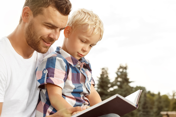 Little boy reading book with dad Stock Photo