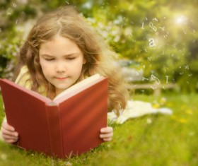 Little girl lying on the grass reading Stock Photo 01