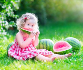 Little girl sitting on the ground eating watermelon Stock Photo