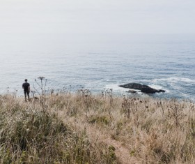Lonely man watching seascape from meadow Stock Photo