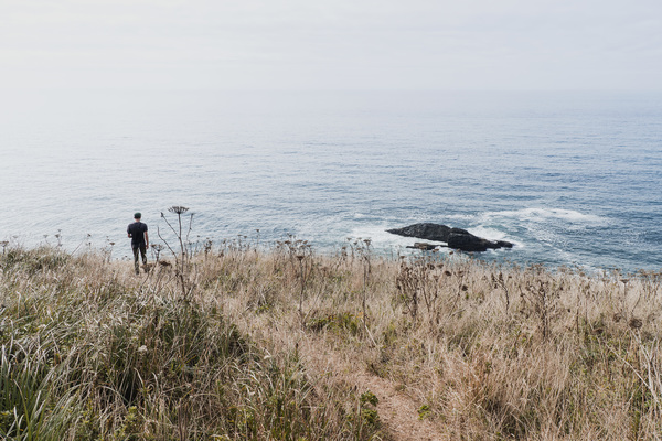 Lonely man watching seascape from meadow Stock Photo