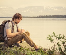 Man sitting by the lake writing Stock Photo