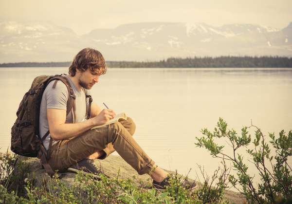 Man sitting by the lake writing Stock Photo