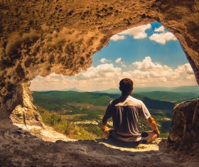 Man sitting in cave mouth meditation Stock Photo