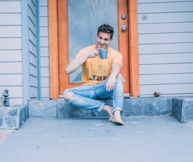 Man sitting in front of the door and drinking beverage Stock Photo