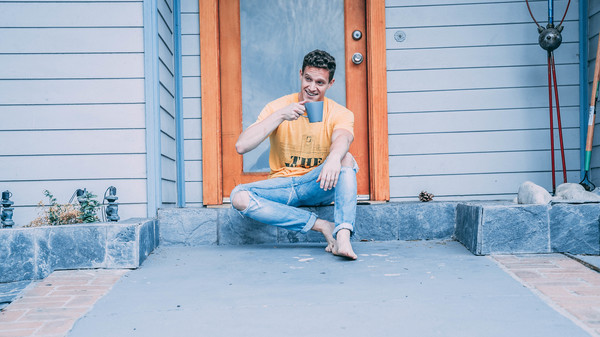 Man sitting in front of the door and drinking beverage Stock Photo