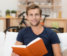Man sitting on sofa reading a book Stock Photo