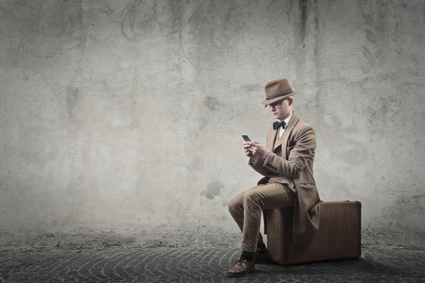 Man sitting on suitcase playing cell phone Stock Photo