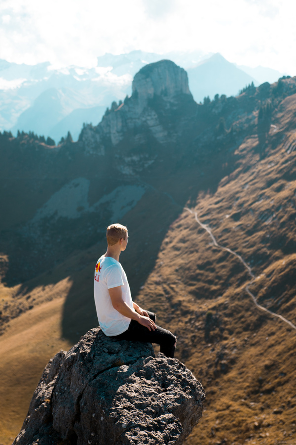 Man sitting on the rock on the mountain and looking at the distant landscape Stock Photo