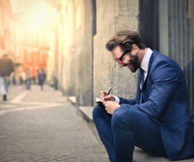 Man sitting on the street recording information smiling Stock Photo