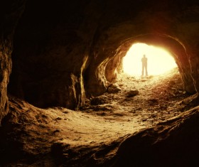 Man standing in a cave mouth Stock Photo