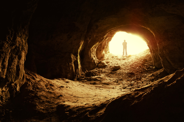 Man standing in a cave mouth Stock Photo