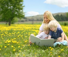 Mom reading a book with her child on the grass Stock Photo