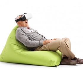 Senior man sitting in inflatable chair looking VR Stock Photo