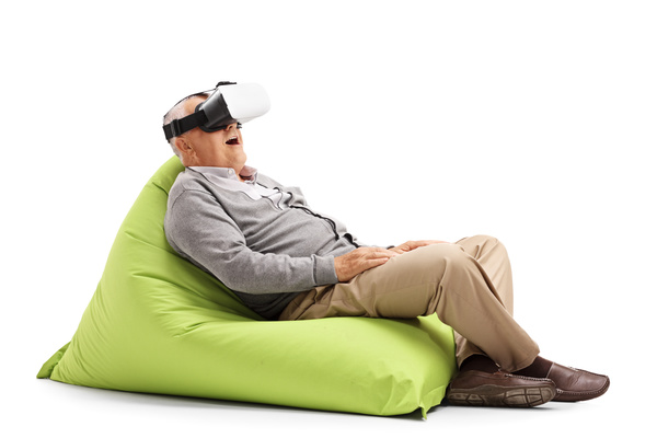 Senior man sitting in inflatable chair looking VR Stock Photo