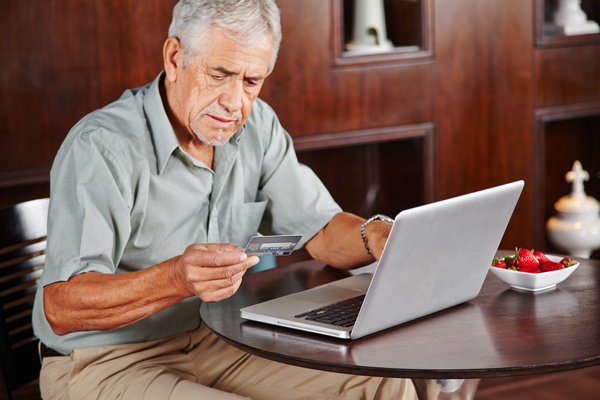 Senior man using laptop for online payment Stock Photo