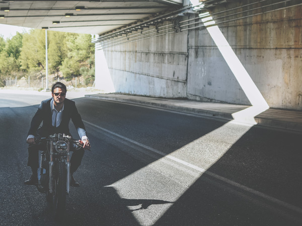 Stylish man riding motorbike on empty road Stock Photo